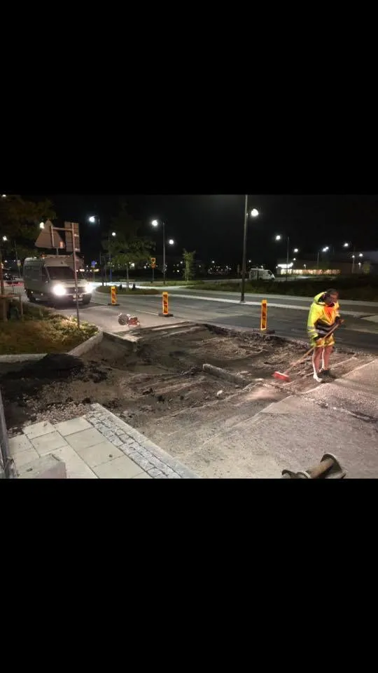 Nattarbete med arbetare som sopar vägyta