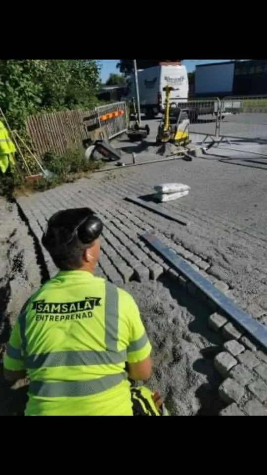 Samsala-arbetare vid stenläggning med varumärkeskläder