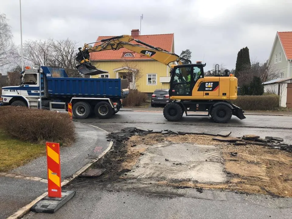 Grävmaskin lastar lastbil på bostadsgata